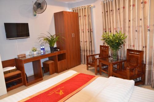 Schlafzimmer mit einem Bett, einem Schreibtisch und einem TV in der Unterkunft New An Phú Hotel in Dong Anh