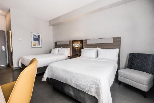 a hotel room with two beds and a chair at Holiday Inn Express Toronto-North York by IHG in Toronto