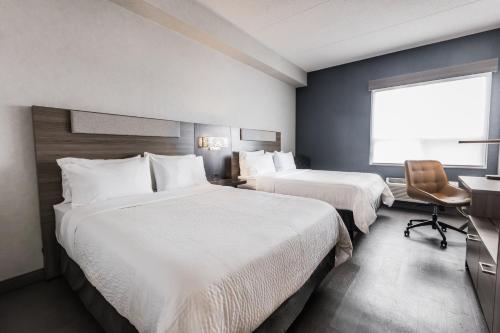 a hotel room with two beds and a desk and a window at Holiday Inn Express Toronto-North York by IHG in Toronto