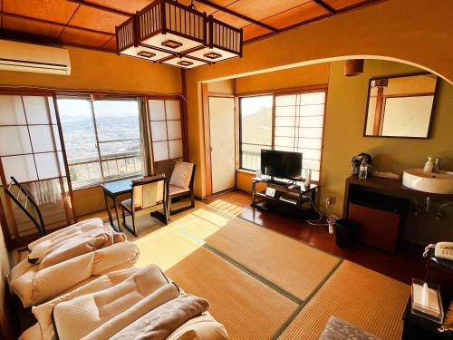 a living room with a couch and a tv at Shiroyama Ryokan in Ikuma