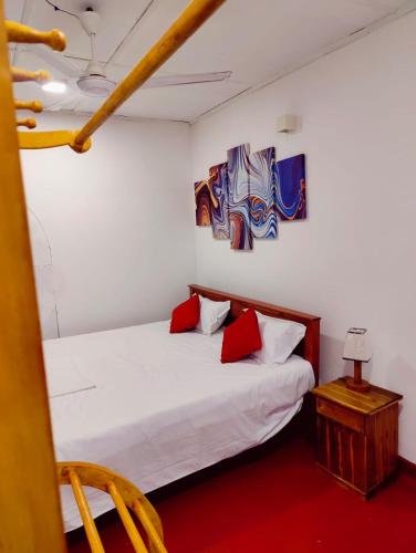 a bedroom with a white bed with two red pillows at Araliya Uyana Residencies Colombo - Entire House with Two Bedrooms in Colombo