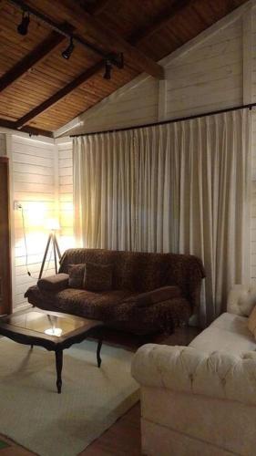 ein Wohnzimmer mit einem Sofa und einem Tisch in der Unterkunft Aconchegante casinha de madeira in Itapema