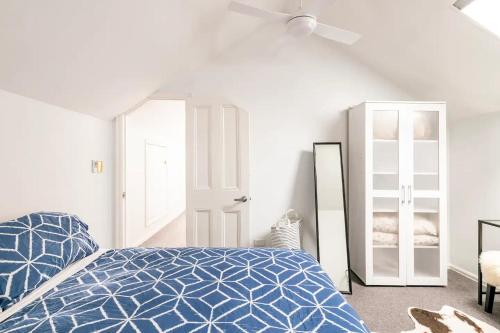 a white bedroom with a blue bed and a mirror at Urban Elegance apartment in Yarraville village in Yarraville
