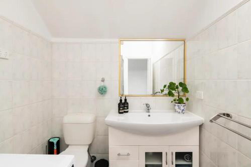 a bathroom with a sink and a toilet and a mirror at Urban Elegance apartment in Yarraville village in Yarraville
