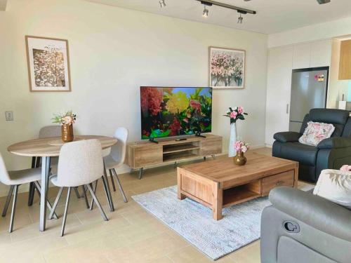 uma sala de estar com um sofá, uma televisão e uma mesa em Sea Pearl Apartment at Waterfront em Darwin