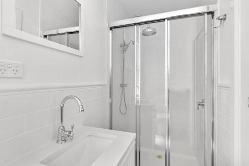a white bathroom with a shower and a sink at Pipers Rest in Yarrawonga