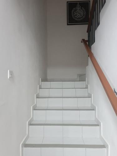 uma escada com degraus brancos e uma imagem na parede em Homestay an nur em Kuantan