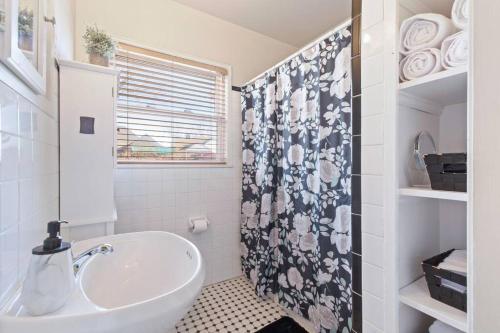 a bathroom with a sink and a shower curtain at Vintage Chic Cottage in Tulsa