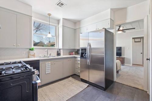 a large kitchen with a stainless steel refrigerator at Tulsa Vintage Chic Cottage - King Bed Expo, TU, Dtwn in Tulsa