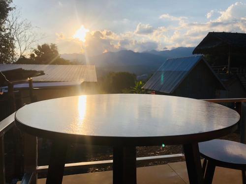 uma mesa numa varanda com o pôr-do-sol ao fundo em Pai Kitchen Hub Hostel em Pai