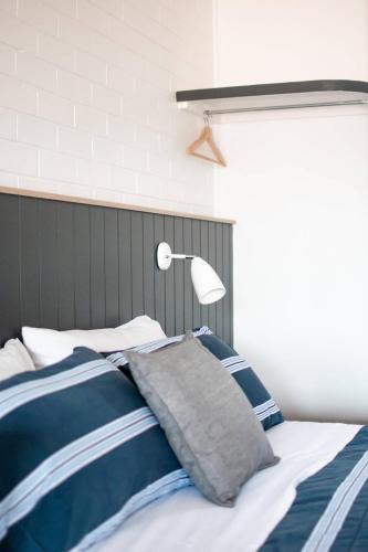 a bed with blue and white sheets and a lamp at Avon River Inn in Stratford