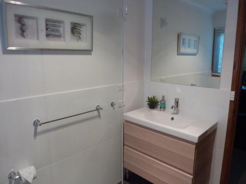ein weißes Badezimmer mit Waschbecken und Spiegel in der Unterkunft Blue Gums Cottage in Kangaroo Valley