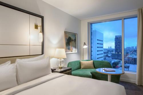 um quarto de hotel com uma cama e uma cadeira e uma janela em The Laura Hotel, Houston Downtown, Autograph Collection em Houston