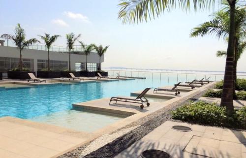 una piscina con bancos, palmeras y el océano en Ecusuites Puerto Santa Ana Bed King Airport, en Guayaquil