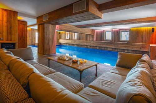a living room with a large couch and a swimming pool at Chalet Temaïa - OVO Network in La Toussuire