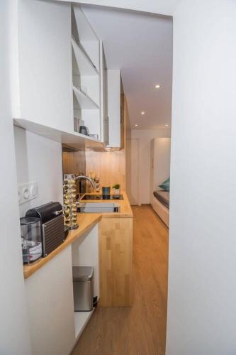 une cuisine avec des armoires blanches et un évier et un lit dans l'établissement Le coin Charmant de Miss K, à Mâcon