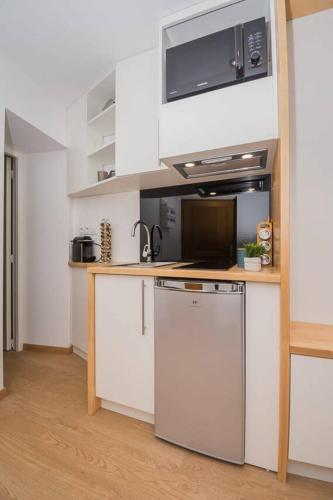 La cuisine est équipée de placards blancs, d'un four micro-ondes et d'un lave-vaisselle. dans l'établissement Le coin Charmant de Miss K, à Mâcon