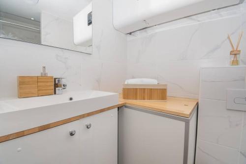 - une cuisine blanche avec un évier et un miroir dans l'établissement T2 Specialtravailleursfamillesetudiants, à Mâcon