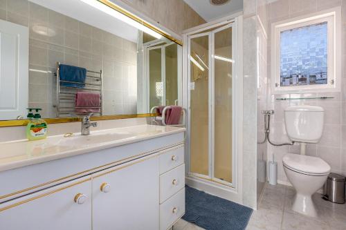 La salle de bains blanche est pourvue de toilettes et d'un lavabo. dans l'établissement Retro 4 bedroom home, warm and welcoming, quiet location, à Porirua