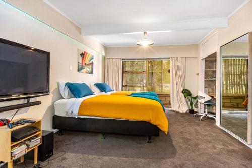 - une chambre avec un grand lit et une télévision dans l'établissement Retro 4 bedroom home, warm and welcoming, quiet location, à Porirua