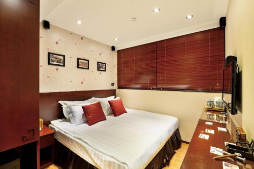 um quarto com uma cama com lençóis brancos e almofadas vermelhas em The Shai Red - formerly Mingle in The Shai em Hong Kong
