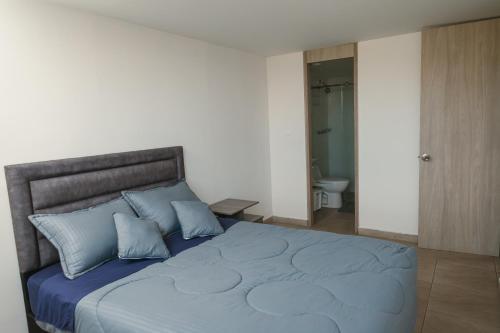 a bedroom with a large bed with blue pillows at El Mirador De Castilla in Manizales