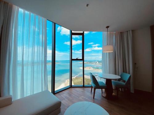 een woonkamer met een tafel en stoelen en een groot raam bij Panoramic sea homestay in Ha Long