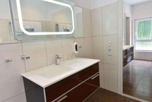 ein Bad mit einem Waschbecken und einem Spiegel in der Unterkunft Hotel Restaurant Waldesruh in Emstek
