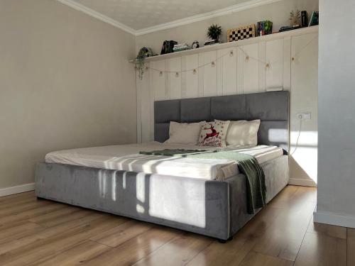 uma cama grande num quarto com piso em madeira em Уютная студия в скандинавском стиле в центре em Astana