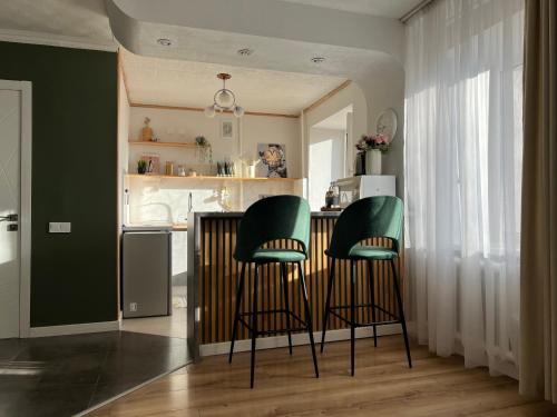 uma cozinha com duas cadeiras verdes num bar em Уютная студия в скандинавском стиле в центре em Astana