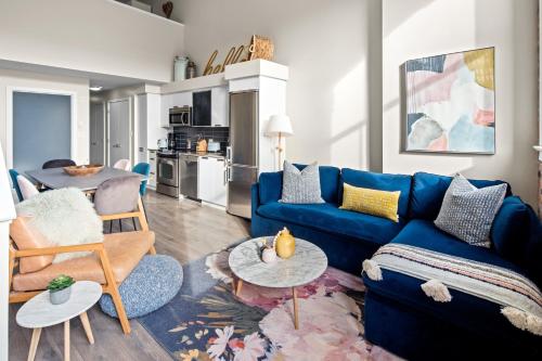 a living room with a blue couch and a table at Trendy 3 bedroom Loft in Chinatown with Parking! in Victoria
