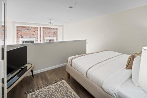 a white bedroom with a bed and a window at Trendy 3 bedroom Loft in Chinatown with Parking! in Victoria