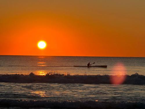 a person in a kayak in the ocean at sunset at Sunny Ocean View Retreat in Perth