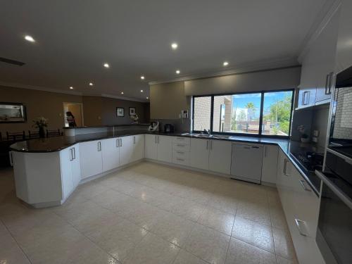 a large kitchen with white cabinets and a large window at Sunny Ocean View Retreat in Perth