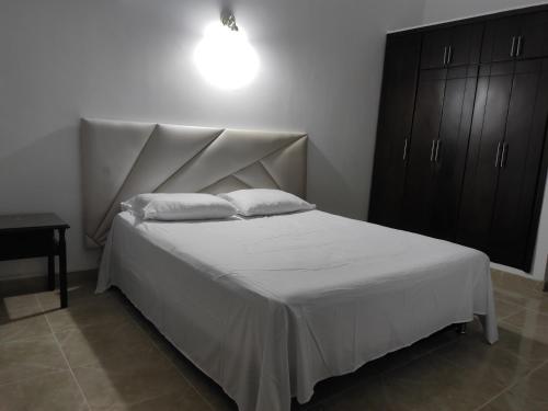 1 dormitorio con 1 cama con sábanas y almohadas blancas en Apartamento, Casa en Buga - Valle, 