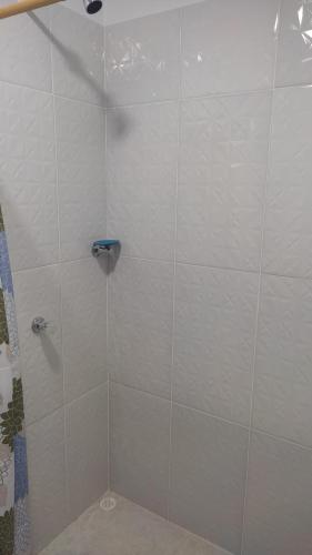 a shower stall with white tiled walls and a shower at Hostal torres del caribe in San Bernardo del Viento