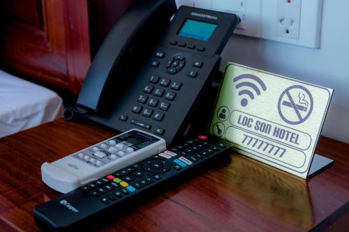 a remote control and a cell phone on a table at Lộc Sơn Hotel in Buon Ma Thuot