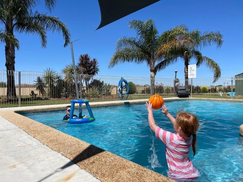 a little girl playing with a basketball in a swimming pool at Kerang Holiday park in Kerang