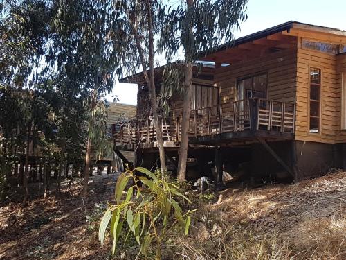 a log cabin with a porch and a balcony at Refugio Nomade Apartamentos in Pichilemu