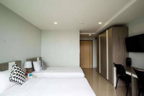 a hotel room with two beds and a desk at ONPA Hotel & Residence Bangsaen in Bangsaen