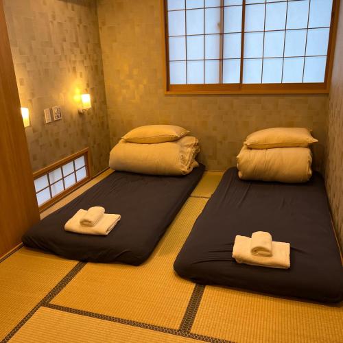 2 Betten in einem Zimmer mit Handtüchern darauf in der Unterkunft Oda hotel Akihabara in Tokio