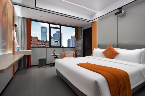 a bedroom with a large bed and a view of a city at MuMu Hotel Changsha in Changsha