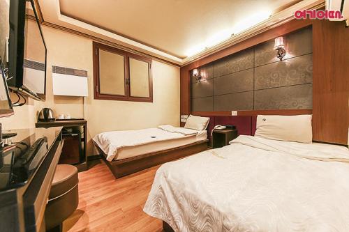 a hotel room with two beds and a desk at Coups Hotel in Seoul