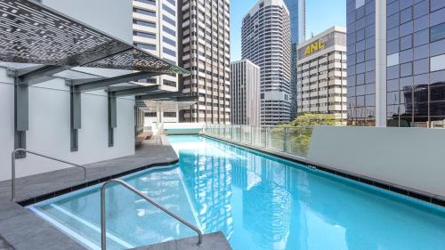 a swimming pool on top of a building with tall buildings at Oaks Brisbane Aurora Suites in Brisbane