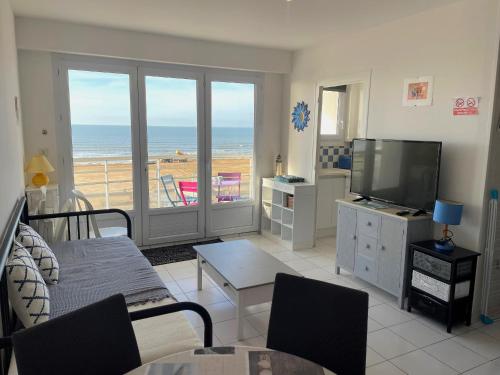 - un salon avec une télévision et une vue sur la plage dans l'établissement Studio moderne face mer avec grand balcon à Saint-Jean-de-Monts, classé 1* - FR-1-323-431, à Saint-Jean-de-Monts