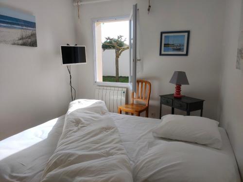 un lit blanc dans une chambre avec une fenêtre dans l'établissement Maison 2 chambres bord de mer, terrasse et jardin, proche commerces et centre-ville - FR-1-323-436, à Saint-Hilaire-de-Riez