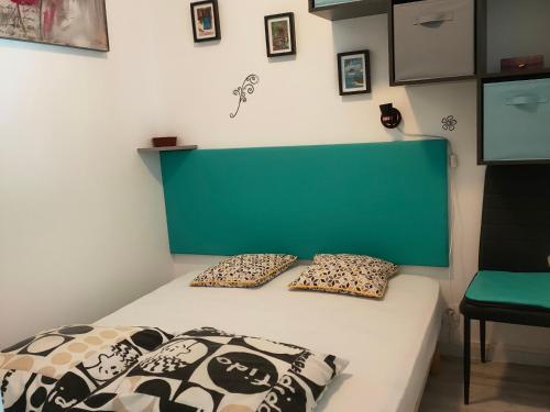 - une chambre avec un lit doté d'une tête de lit et d'oreillers verts dans l'établissement Appartement cosy à 220m de la plage avec terrasse privée, proche centre et forêt - St Jean de Monts - FR-1-323-463, à Saint-Jean-de-Monts