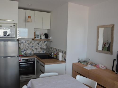 une cuisine avec des armoires blanches et un réfrigérateur en acier inoxydable dans l'établissement Appartement cosy à 50m de la plage pour 4 pers. avec balcon à Saint Hilaire de Riez - FR-1-323-448, à Saint-Hilaire-de-Riez