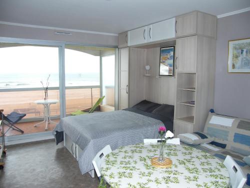 - une chambre avec un lit et une table et une vue sur la plage dans l'établissement Studio lumineux face mer avec balcon et parking privé, à 500m des commerces - FR-1-323-450, à Saint-Jean-de-Monts