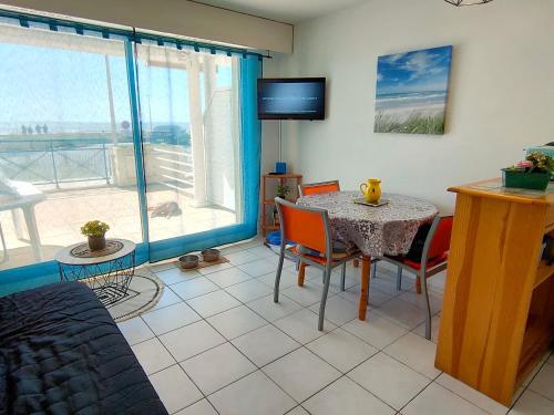 un salon avec une table, des chaises et une télévision dans l'établissement Appartement Front de Mer avec Terrasse, Proche École de Voile - 4 Pers, Saint-Hilaire-de-Riez - FR-1-323-455, à Saint-Hilaire-de-Riez